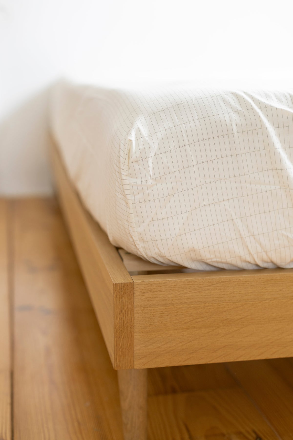 Hoek van het Earthle aardingshoeslaken om het matras op een houten bed, 200 x 160 x 30 cm