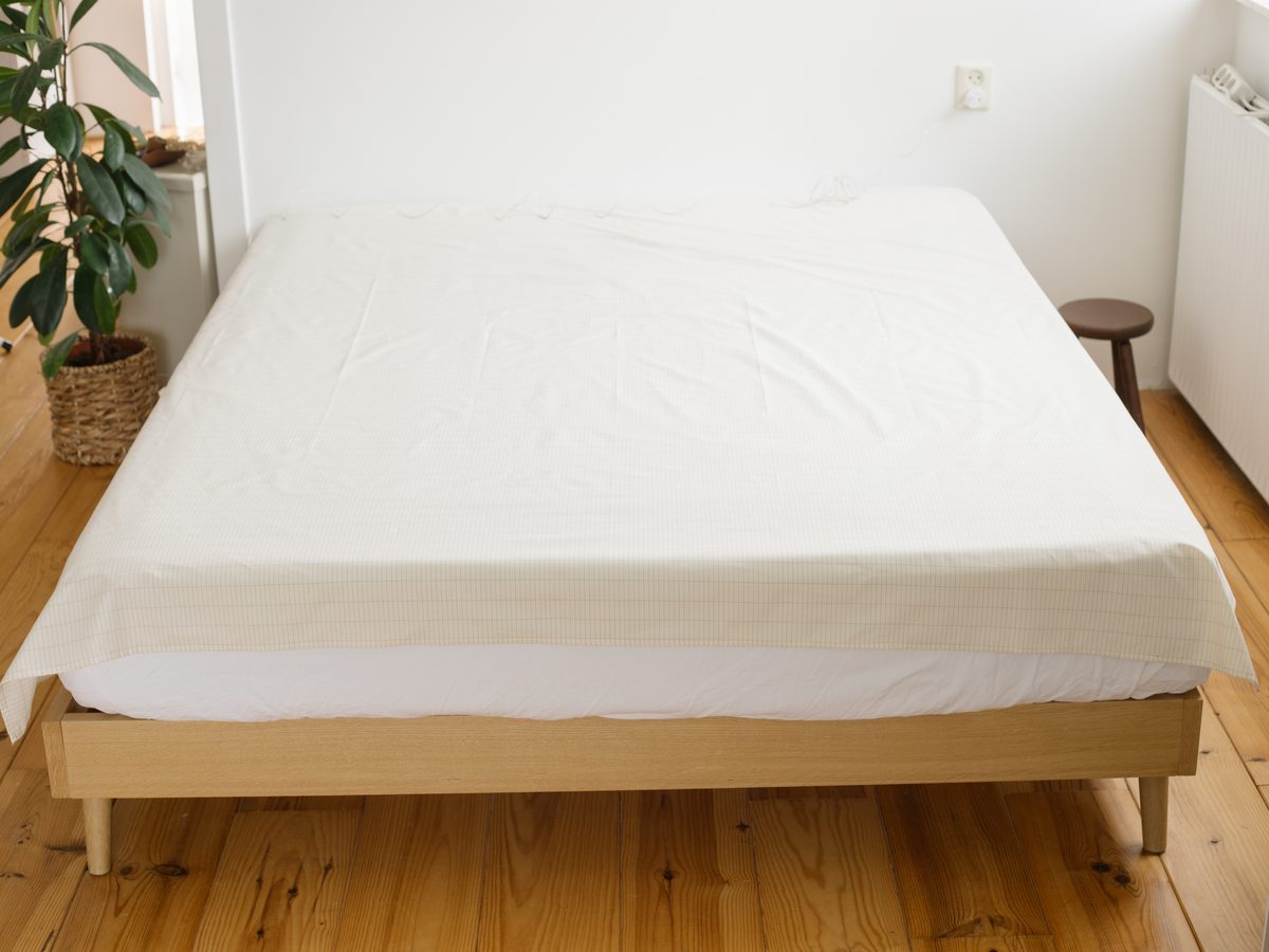 Aardings hoeslaken strak om een matras in een lichte slaapkamer