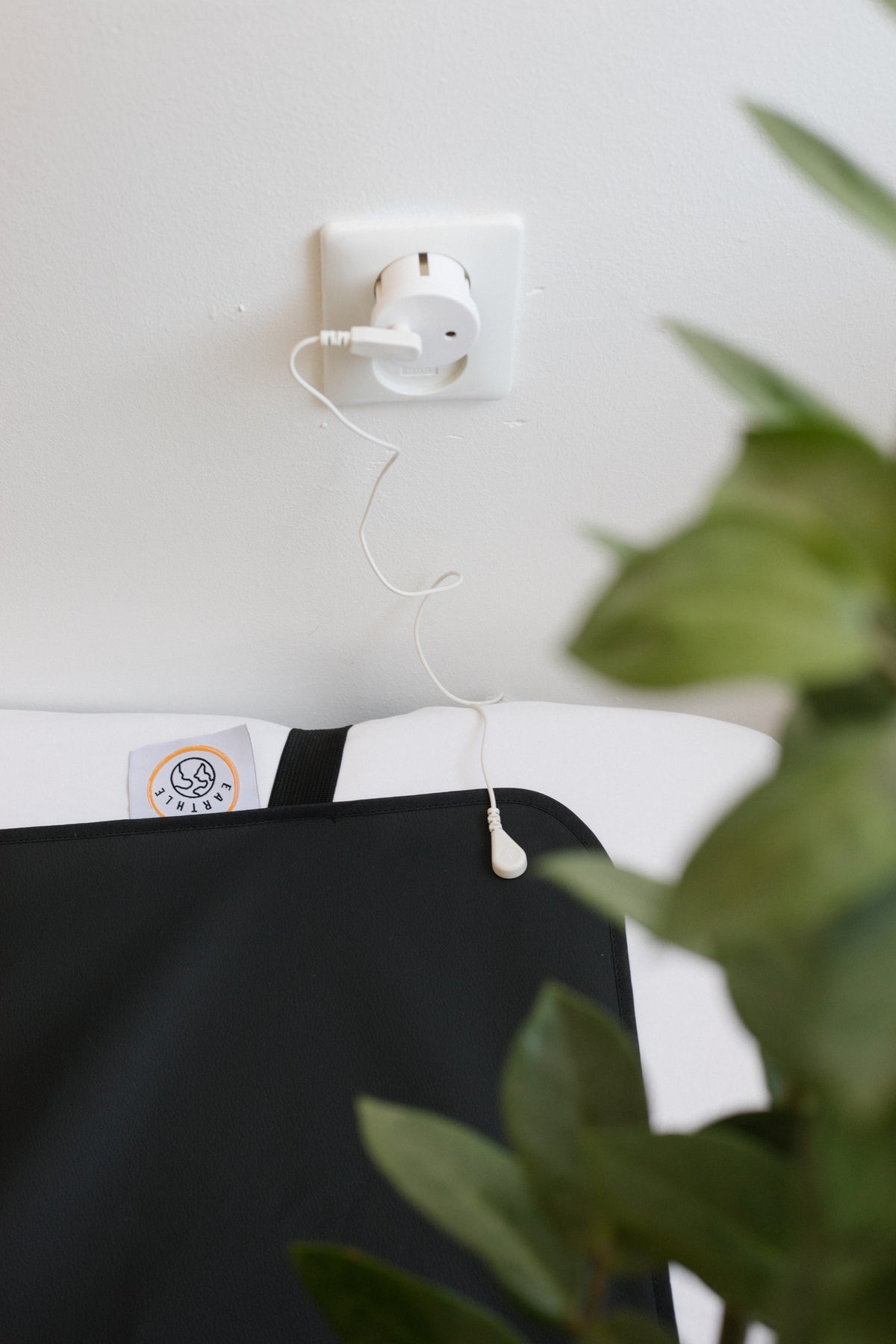 Earthle Erdungsstecker in einer geerdeten Steckdose, mit dem Kabel zur Schlafmatte