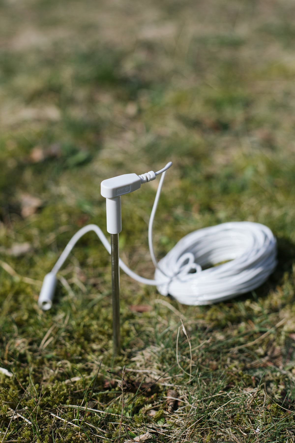 Earthle Erdungsstab im Erdreich, daneben das aufgerollte Kabel